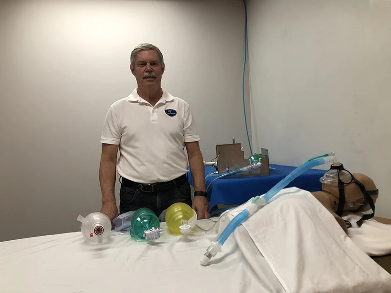 Man standing above a dummy wearing a breathing mask